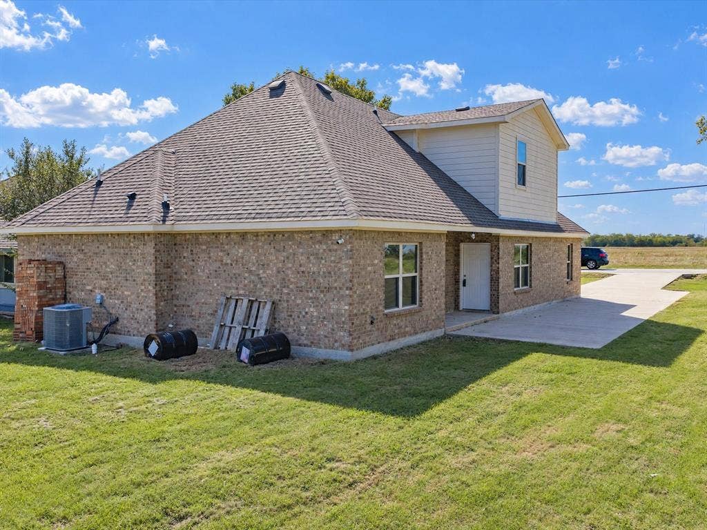 2312 Rogers Avenue, Lancaster, TX 75134 Multi-level exterior featuring a brick and composite siding facade, a composition shingle roof, a concrete driveway, and a concrete patio