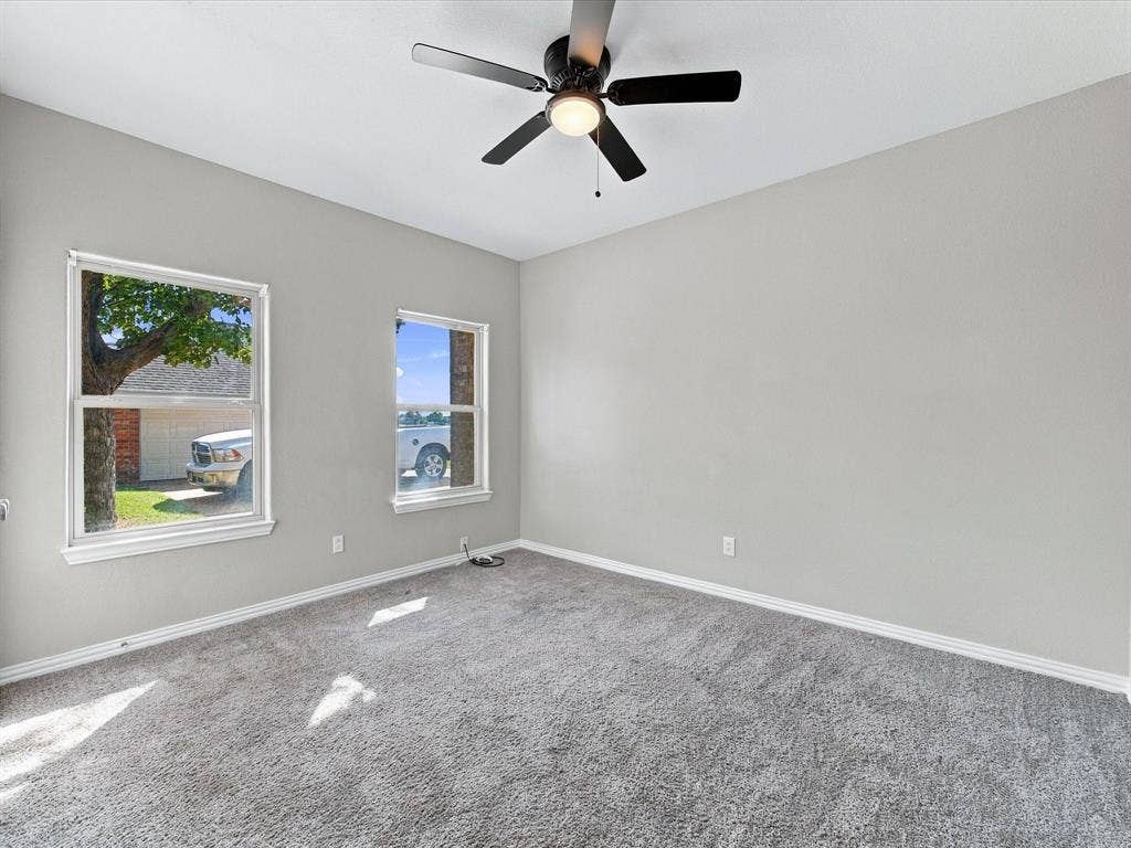 2312 Rogers Avenue, Lancaster, TX 75134 Neutral-toned interior space featuring wall-to-wall carpeting, dual windows, and an integrated ceiling fan with a centered light fixture