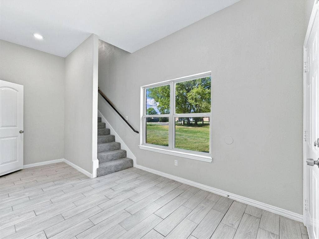 2312 Rogers Avenue, Lancaster, TX 75134 Interior space featuring wood-finish tile flooring, recessed lighting, carpeted staircase with a dark handrail, and large-format windows