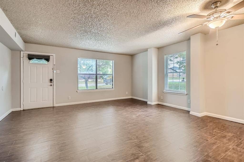 806 Prairie Creek Drive, Princeton, TX 75407 Living area featuring wood-finish tile flooring, a multi-blade ceiling fan with integrated lighting, dual windows, and a multi-panel entry door