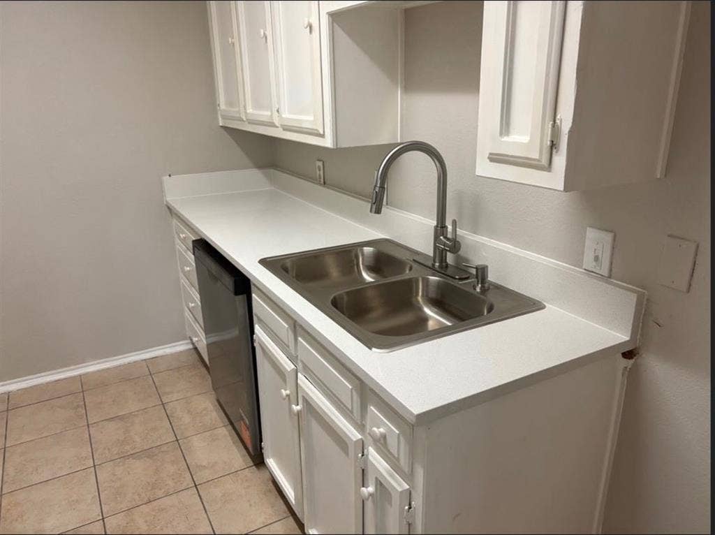 806 Prairie Creek Drive, Princeton, TX 75407 Kitchen featuring white cabinetry, solid-surface countertops, dual-basin stainless steel sink with high-arc pull-down faucet, and ceramic tile flooring
