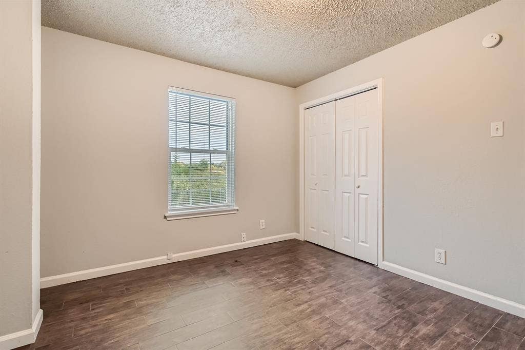 806 Prairie Creek Drive, Princeton, TX 75407 Room featuring wood-finish flooring, a single-pane window, and a built-in closet with double doors