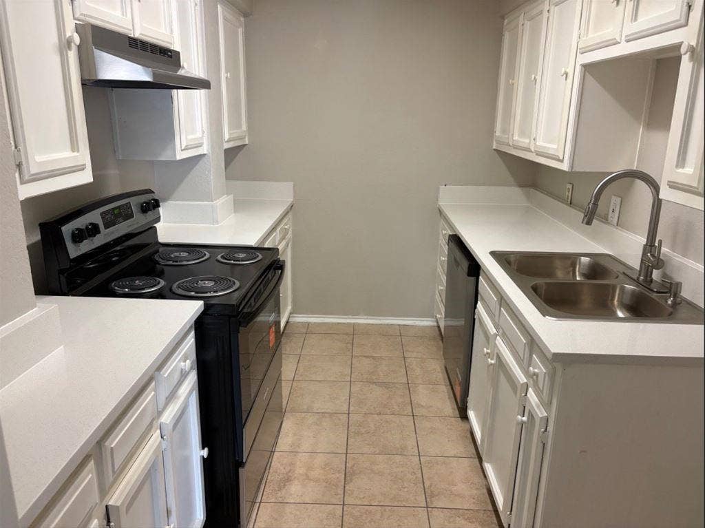 806 Prairie Creek Drive, Princeton, TX 75407 Kitchen featuring white cabinetry, light-toned solid surface countertops, a dual-basin stainless steel sink with a high-arch faucet, black range, and tile flooring