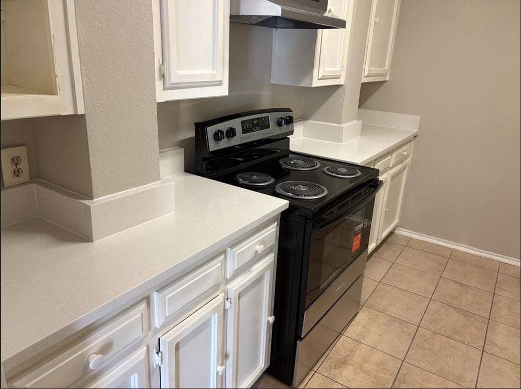 806 Prairie Creek Drive, Princeton, TX 75407 Kitchen featuring white cabinetry, light-toned solid surface countertops, a black electric range, an overhead vent hood, and tiled flooring