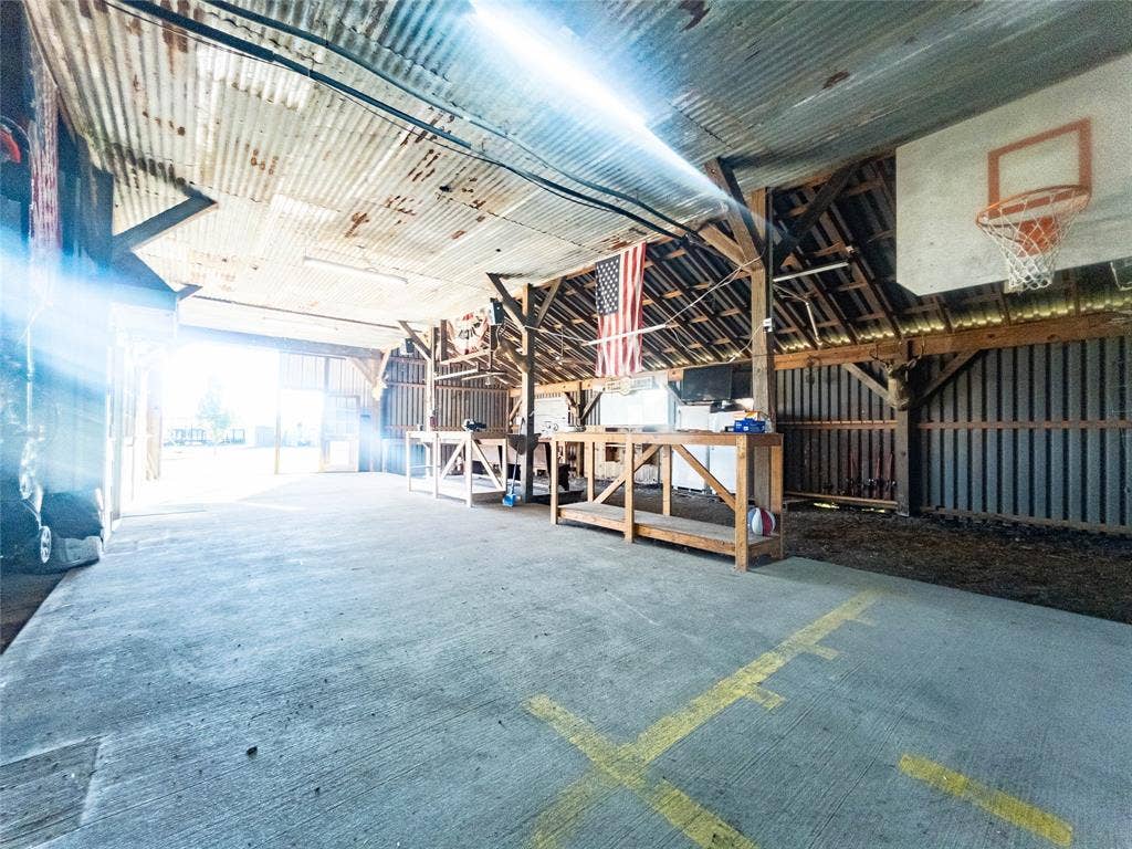1154 Outlaw Trail, Wolfe City, TX 75496 Expansive outbuilding featuring exposed timber framing, corrugated metal roofing, concrete flooring, and an integrated backboard