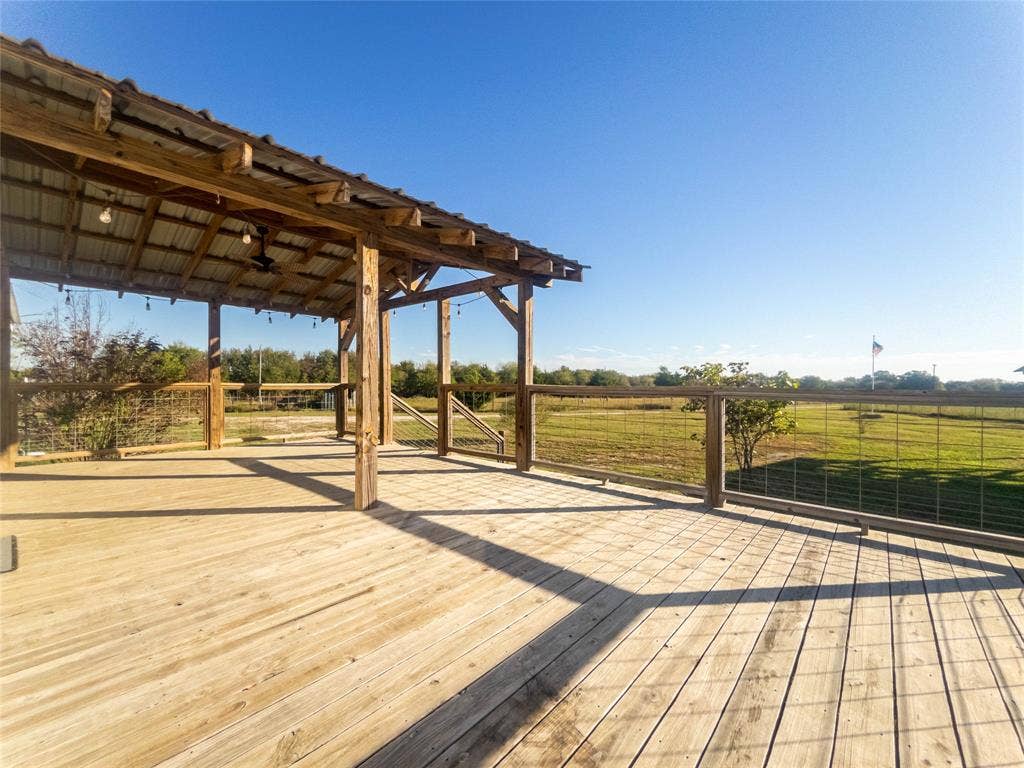 1154 Outlaw Trail, Wolfe City, TX 75496 Expansive wood deck featuring a covered timber-framed pavilion, metal roof, and wire mesh perimeter railing