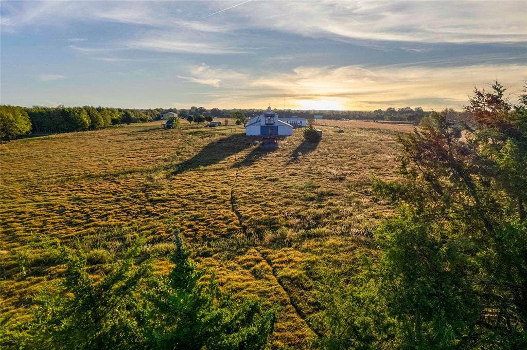 1154 Outlaw Trail, Wolfe City, TX 75496 Expansive acreage featuring open pasture land, mature perimeter trees, and a detached outbuilding