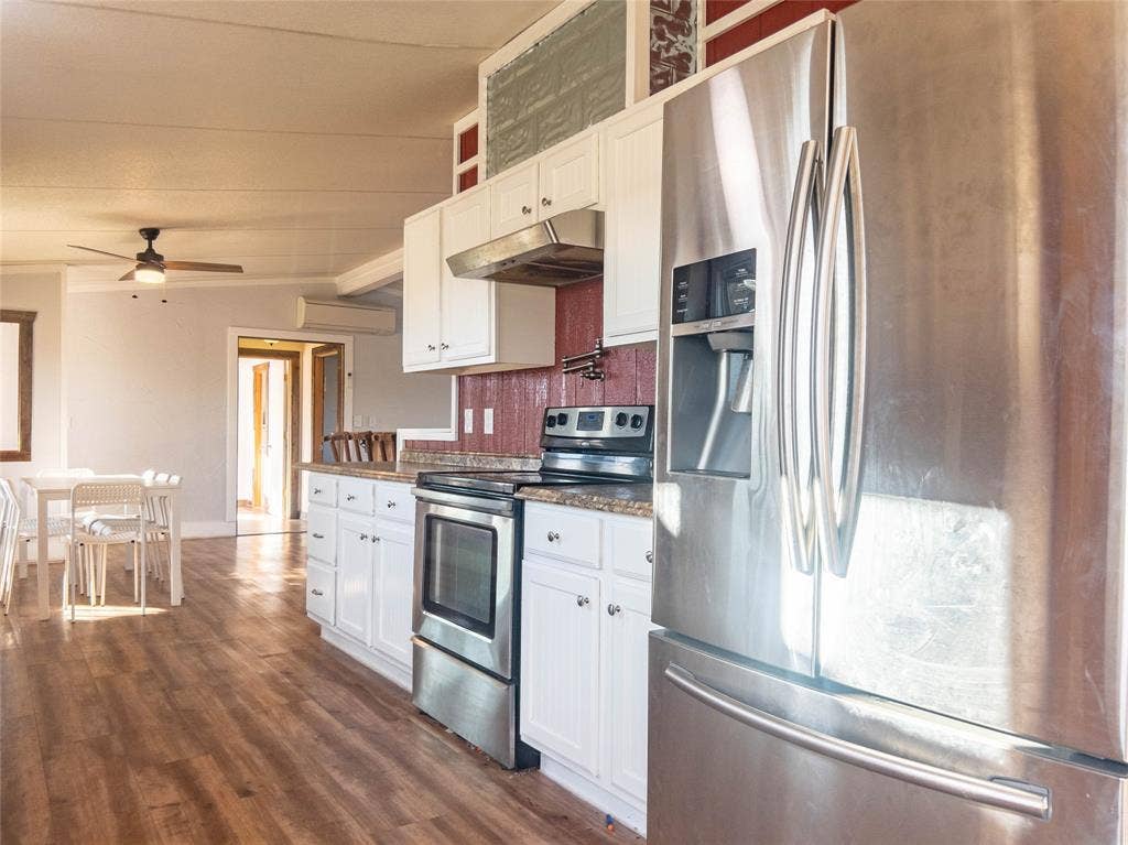 1154 Outlaw Trail, Wolfe City, TX 75496 Kitchen featuring white cabinetry, stainless steel appliances, wood-finish flooring, and a ceiling fan
