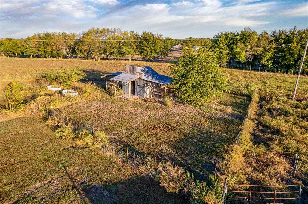 1154 Outlaw Trail, Wolfe City, TX 75496 Rural property featuring a structure with a metal roof, expansive open acreage, and perimeter fencing