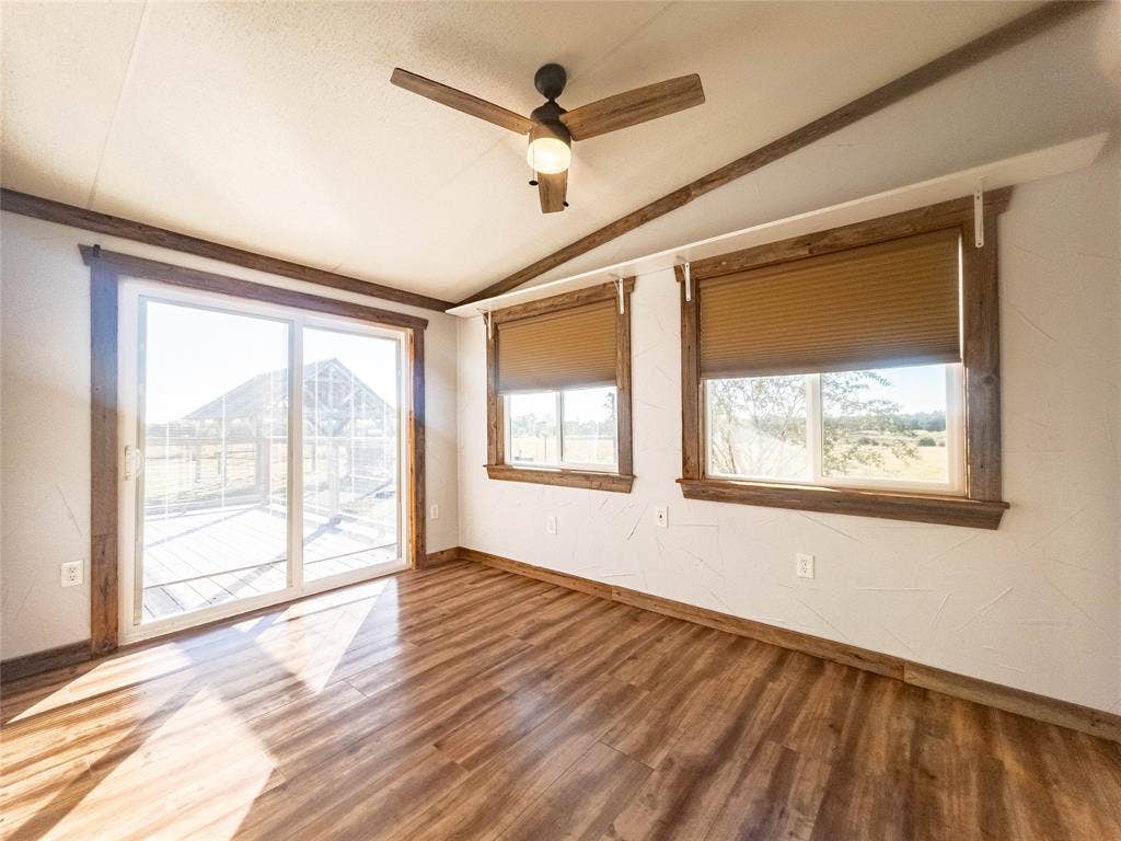 1154 Outlaw Trail, Wolfe City, TX 75496 Wood-finish flooring, sliding glass door, dual pane windows with integrated window shades, wood-trim accents, and a ceiling fan with light fixture