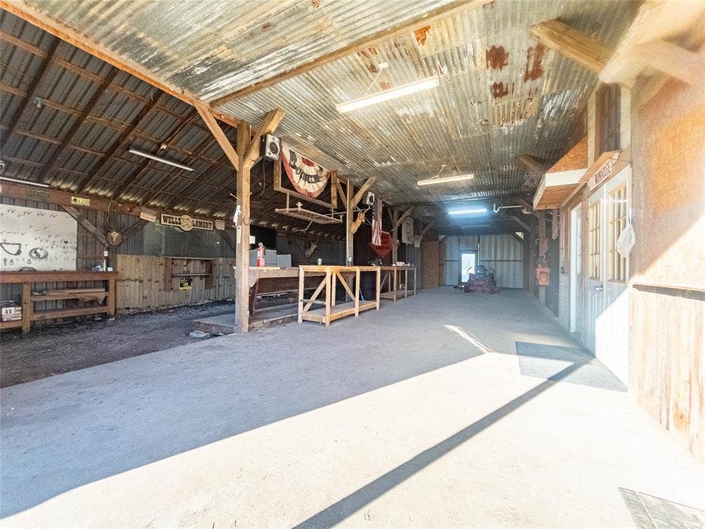 1154 Outlaw Trail, Wolfe City, TX 75496 Enclosed barn structure featuring a concrete floor, corrugated metal ceiling, exposed timber post-and-beam construction, and multiple built-in wooden workbenches