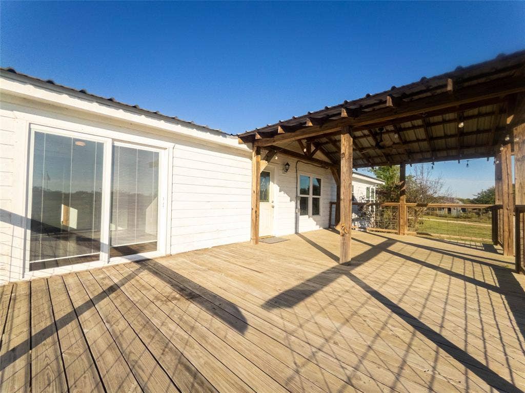1154 Outlaw Trail, Wolfe City, TX 75496 Expansive wood-plank deck featuring a covered timber-framed patio, metal roofing, and cable-rail fencing