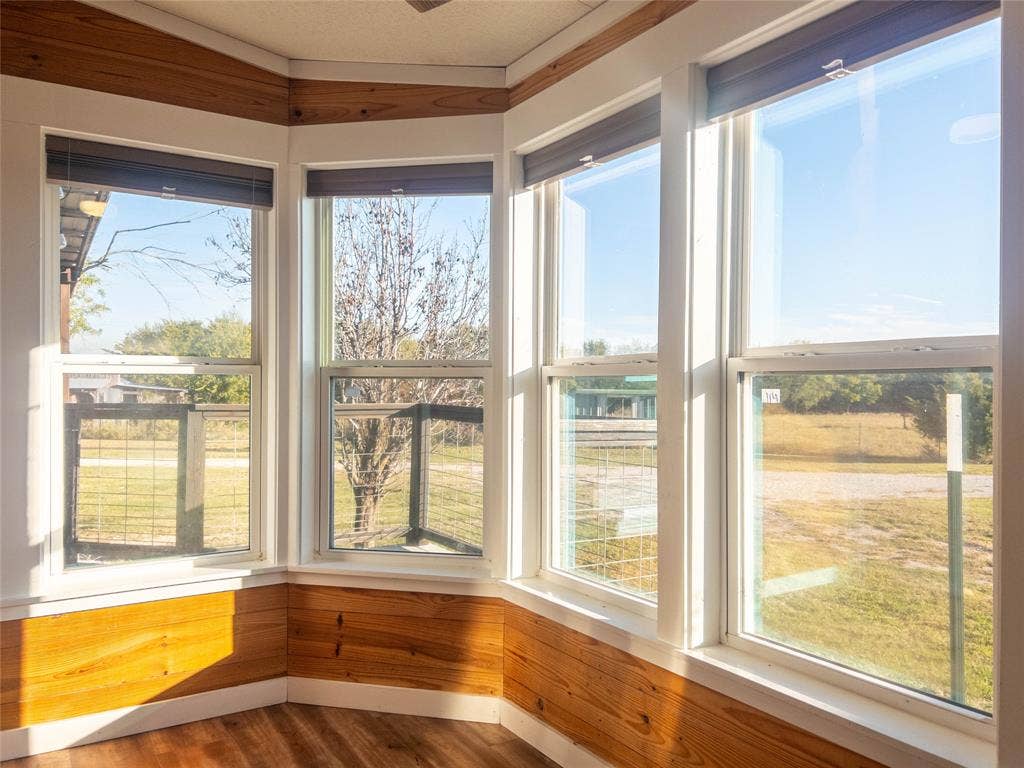 1154 Outlaw Trail, Wolfe City, TX 75496 Bay window featuring multi-pane glass, natural wood-finish wainscoting, white trim, and retractable shades