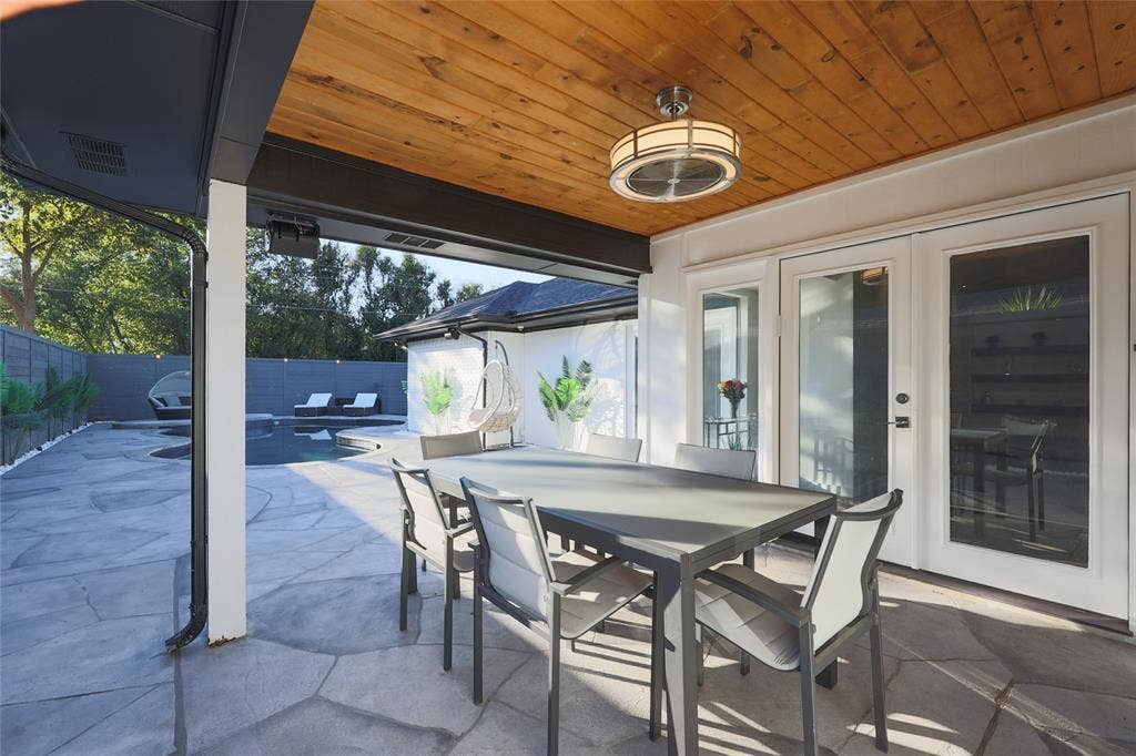 Covered patio featuring a stained wood plank ceiling, recessed ceiling fan with integrated lighting, flagstone flooring, and dual-pane glass entry doors