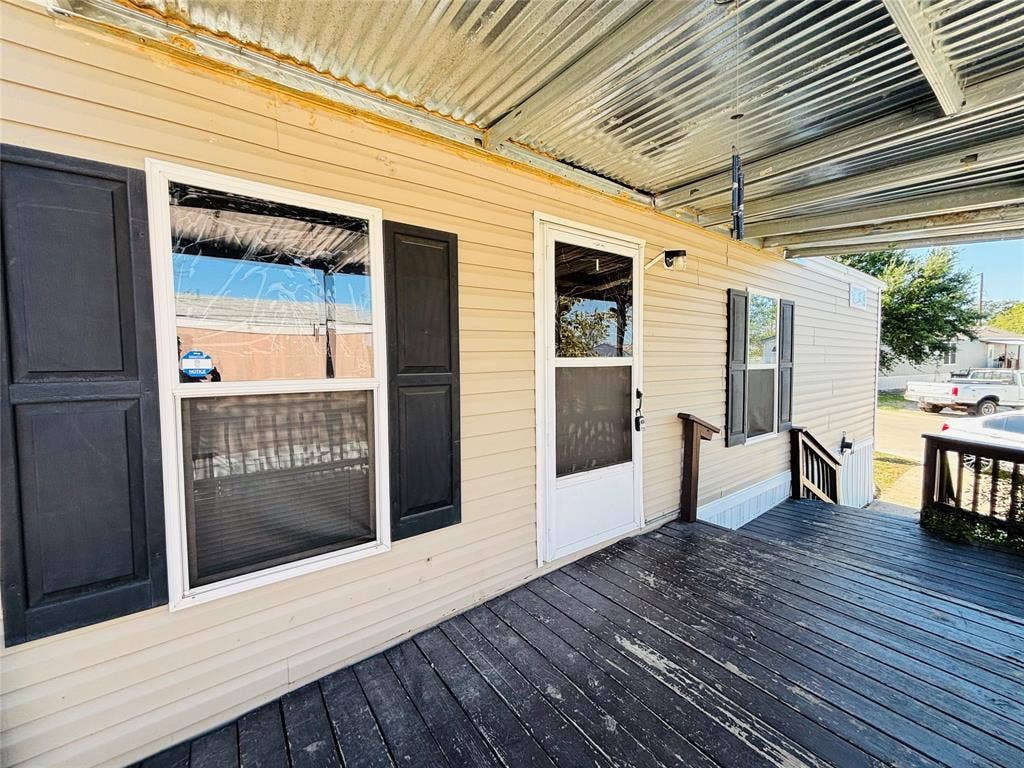 14311 Skyfrost Drive, #116, Dallas, TX 75253 Exterior featuring horizontal siding, dark-toned shutters, a covered wooden deck, and a corrugated metal awning