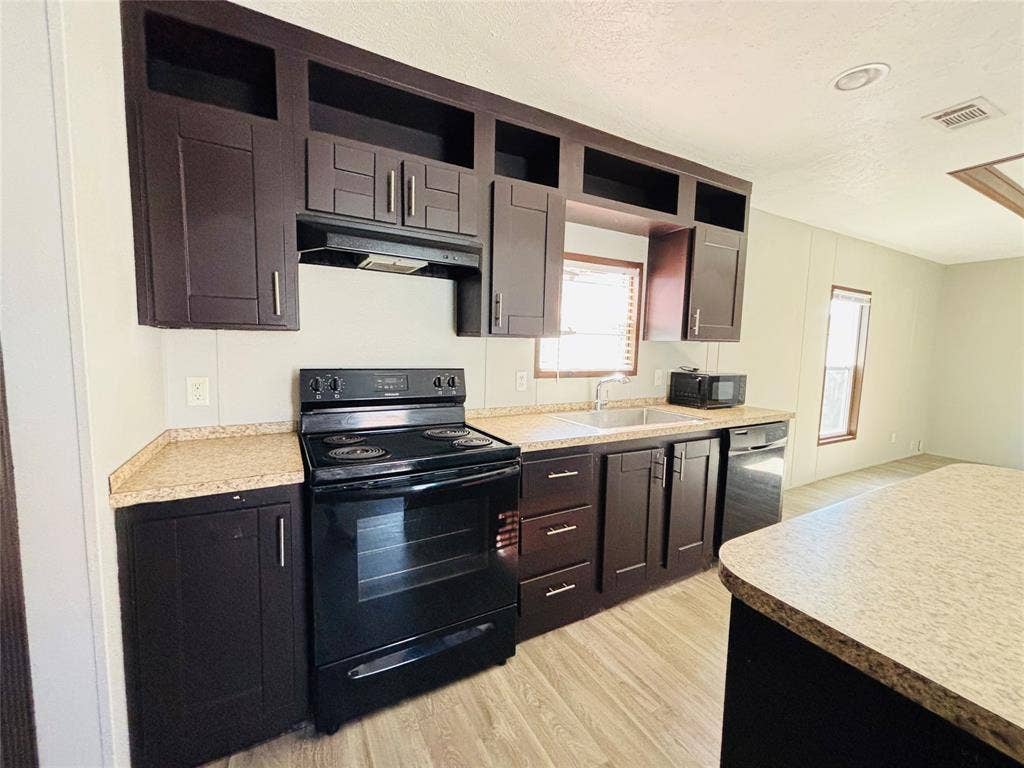 14311 Skyfrost Drive, #116, Dallas, TX 75253 Kitchen featuring dark cabinetry with crown molding, stone-patterned countertops, recessed lighting, and wood-finish flooring