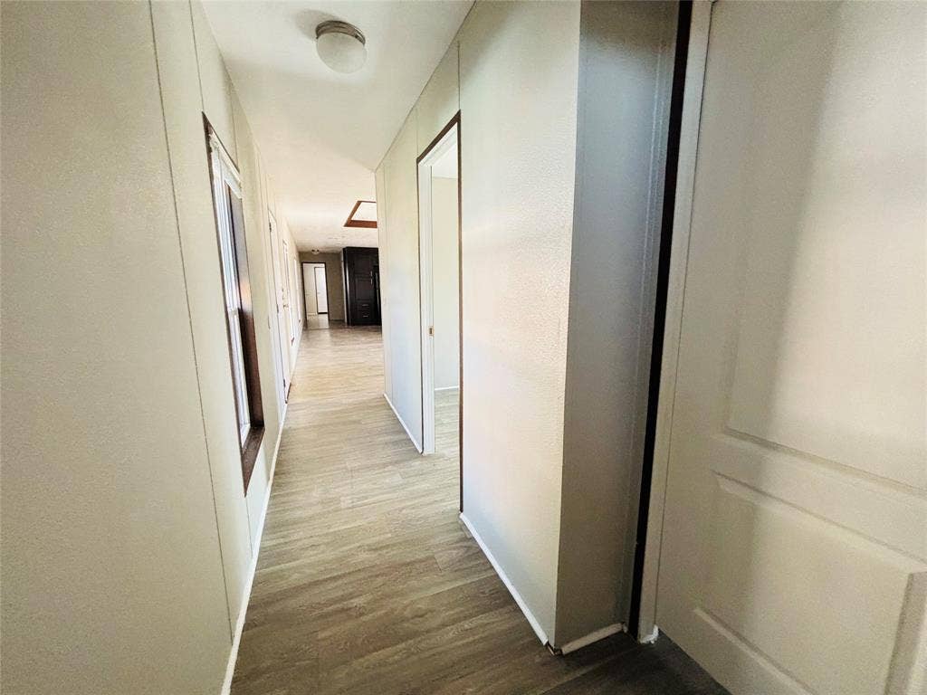 14311 Skyfrost Drive, #116, Dallas, TX 75253 Hallway featuring wood-finish flooring, neutral wall tones, ceiling-mounted lighting, and paneled interior doors