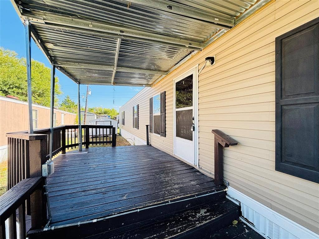 14311 Skyfrost Drive, #116, Dallas, TX 75253 Exterior wood-plank deck featuring a metal-corrugated roof covering, dark-stained railing, and exterior shutters