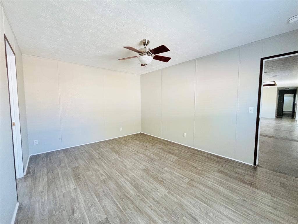 14311 Skyfrost Drive, #116, Dallas, TX 75253 Room featuring light-toned paneling, wood-finish flooring, and a ceiling-mounted light fixture with a fan