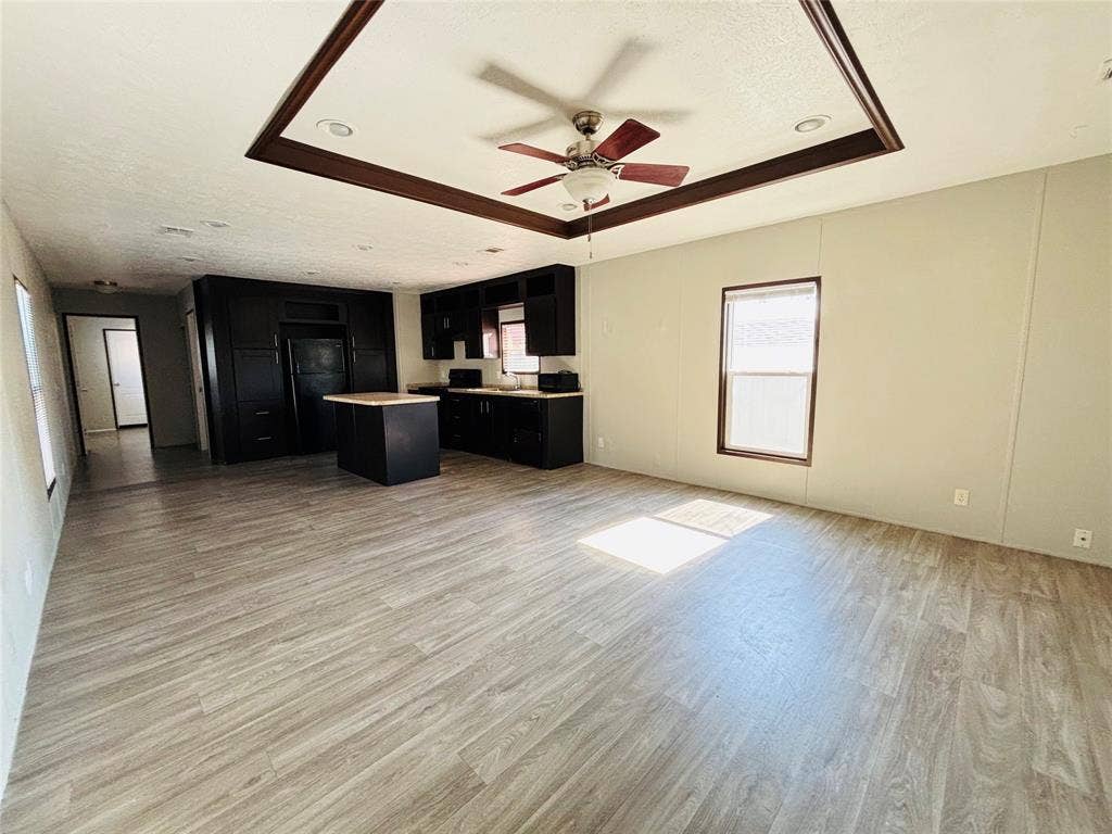 14311 Skyfrost Drive, #116, Dallas, TX 75253 Open-concept interior featuring wood-finish flooring, tray ceiling with recessed lighting, and a kitchen equipped with dark cabinetry and a central island