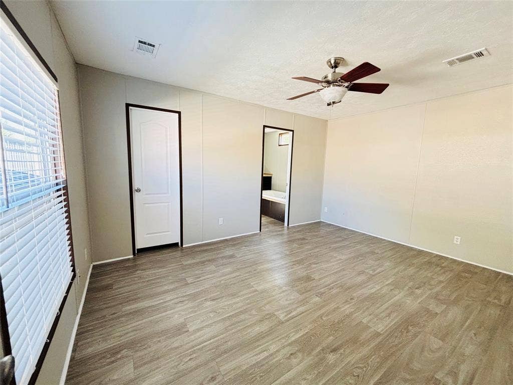 14311 Skyfrost Drive, #116, Dallas, TX 75253 Neutral-toned interior featuring wood-finish flooring, a ceiling fan with integrated lighting, and a white arched-panel door