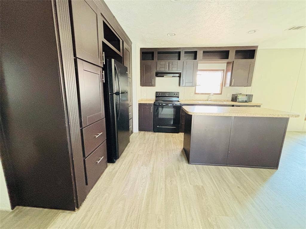 14311 Skyfrost Drive, #116, Dallas, TX 75253 Kitchen featuring dark cabinetry, expansive center island with countertop seating, stone-finish countertops, recessed lighting, and wood-finish flooring