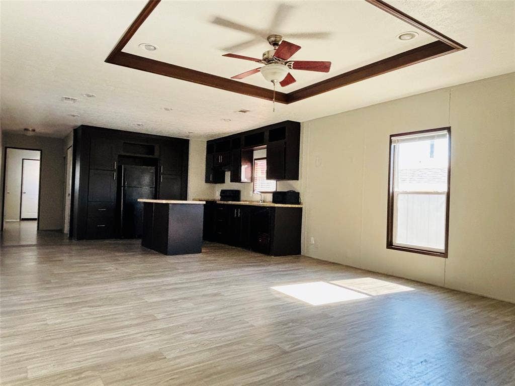 14311 Skyfrost Drive, #116, Dallas, TX 75253 Open-concept kitchen featuring dark cabinetry, a central island, recessed lighting, wood-finish flooring, and a tray ceiling with a built-in ceiling fan