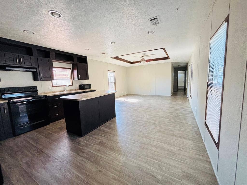 14311 Skyfrost Drive, #116, Dallas, TX 75253 Kitchen featuring dark cabinetry, an island with stone-finish countertop, wood-finish flooring, recessed lighting, and a coffered ceiling with integrated ceiling fan