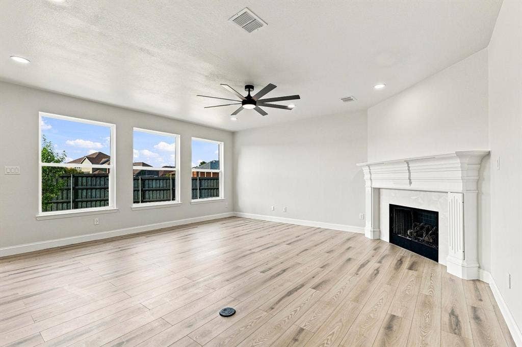 4421 Red Barn, Richardson, TX 75082 Living area featuring wood-finish flooring, a white decorative fireplace mantel, three large windows, recessed lighting, and a multi-blade ceiling fan