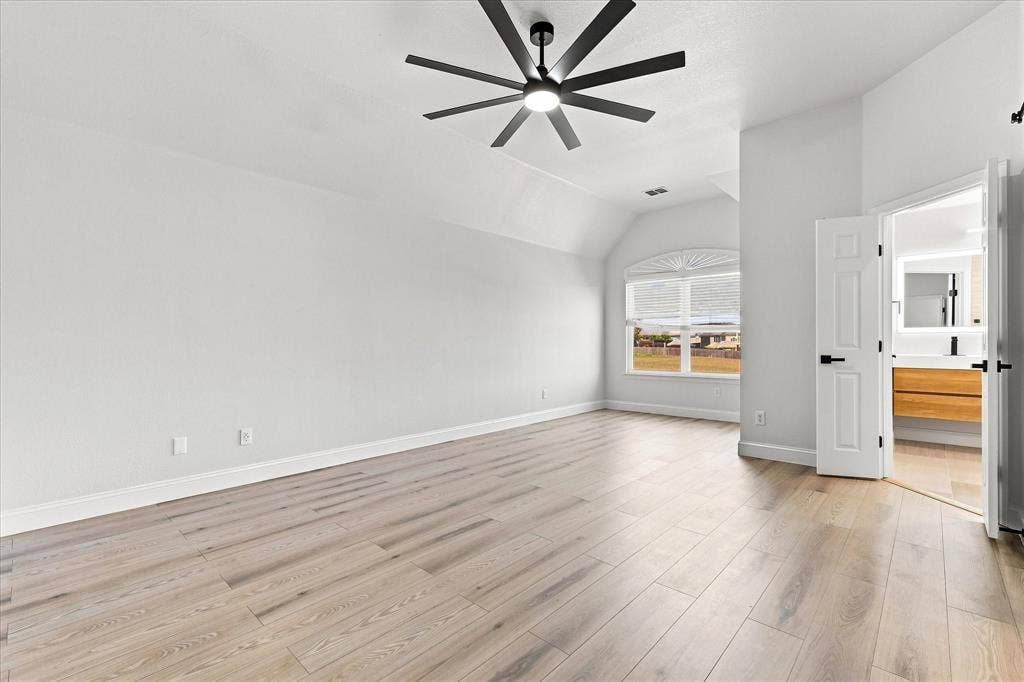 4421 Red Barn, Richardson, TX 75082 Vaulted ceilings, wood-finish flooring, multi-blade modern ceiling fan, arched window, and paneled doors with matte black hardware