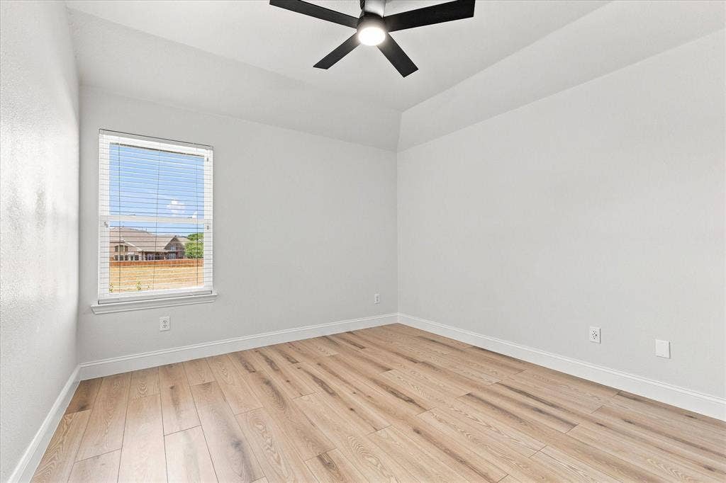 4421 Red Barn, Richardson, TX 75082 Neutral-toned interior room featuring wood-finish flooring, tray ceiling, and a modern black ceiling fan with integrated lighting