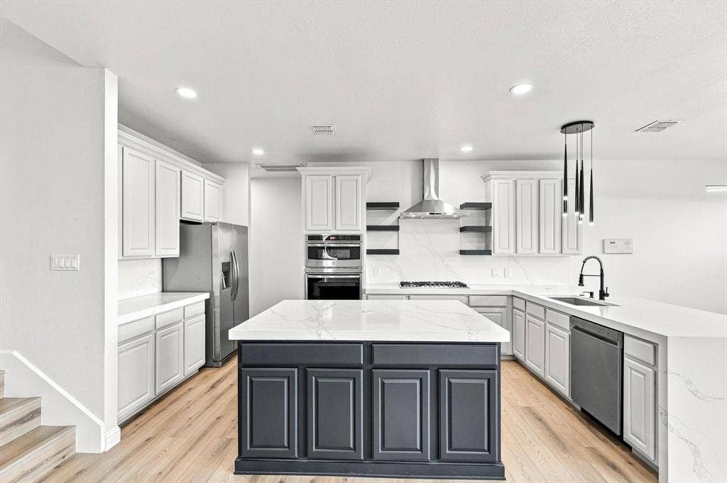 4421 Red Barn, Richardson, TX 75082 Kitchen featuring white cabinetry, a contrasting dark-toned center island with quartz countertops, stainless steel appliances, stone-look backsplash, and wood-finish flooring