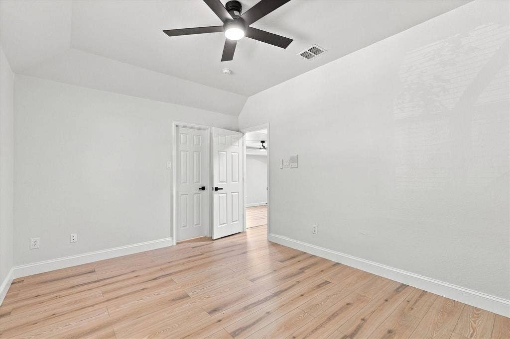 4421 Red Barn, Richardson, TX 75082 Room featuring wood-finish flooring, tray ceiling, and a matte black ceiling fan with integrated lighting