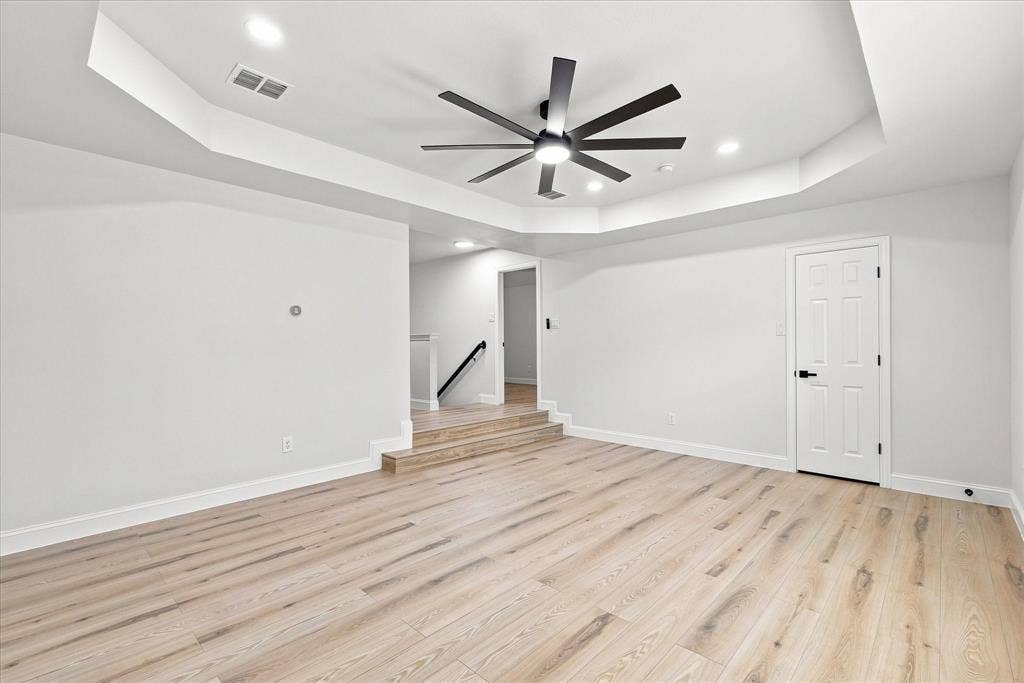 4421 Red Barn, Richardson, TX 75082 Tray ceiling featuring a multi-blade ceiling fan, recessed lighting, and wood-finish flooring with a step-up elevation change