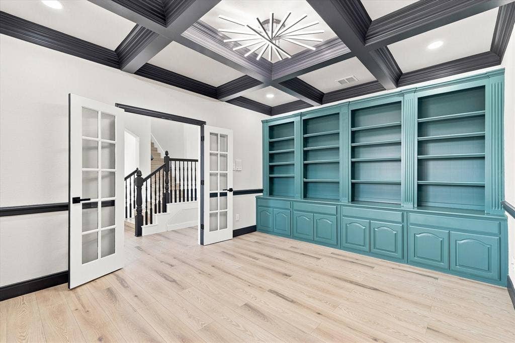 4421 Red Barn, Richardson, TX 75082 Coffered ceiling with contrasting dark beams, custom built-in teal shelving, wood-finish flooring, glass-paneled French doors, and recessed lighting