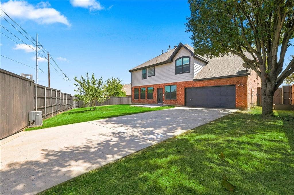 4421 Red Barn, Richardson, TX 75082 Exterior featuring brick and horizontal siding construction, an attached two-car garage, an expansive concrete driveway, a privacy fence, and mature trees