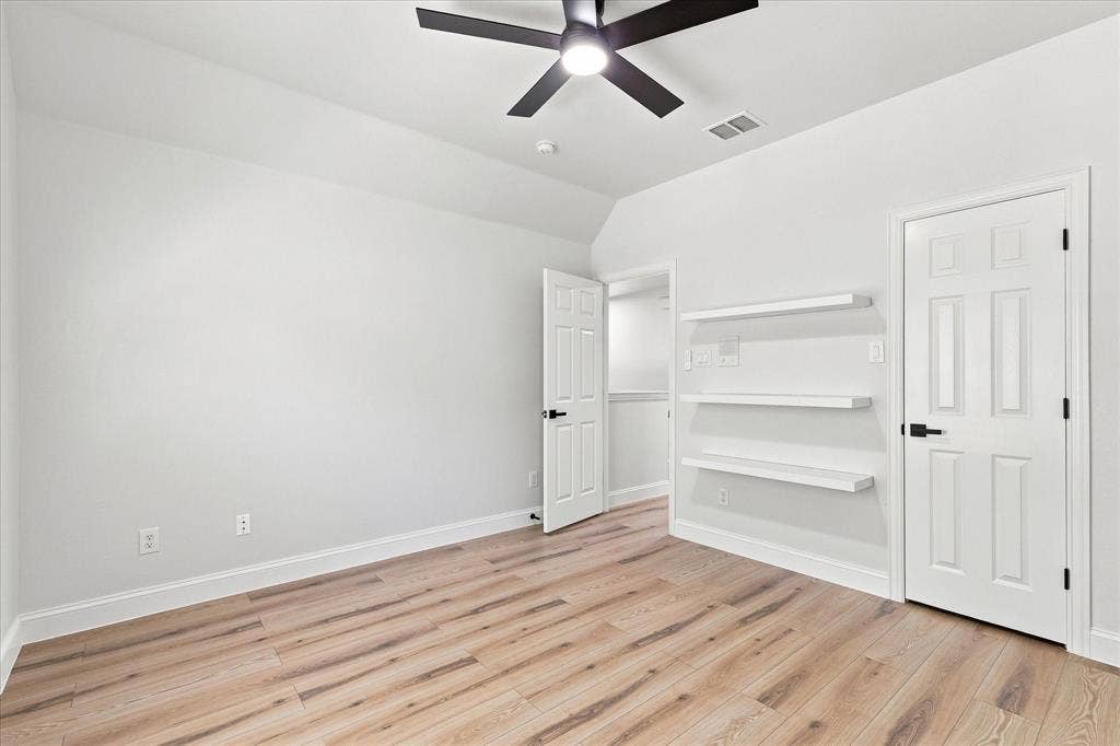 4421 Red Barn, Richardson, TX 75082 Room featuring wood-finish flooring, three built-in wall shelves, a matte black ceiling fan, and six-panel doors with matte black hardware