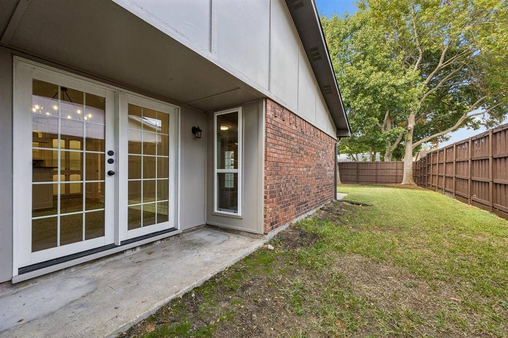 1213 Lombardy Drive, Plano, TX 75023 A charming outdoor area combines a concrete patio, classic brick construction, and French doors with a private, fenced backyard. The side yard extends the outdoor space, while mature trees and established greenery contribute natural appeal. Whether enjoying a quiet morning outdoors or hosting casual gatherings, this setting offers a welcoming extension of the home.