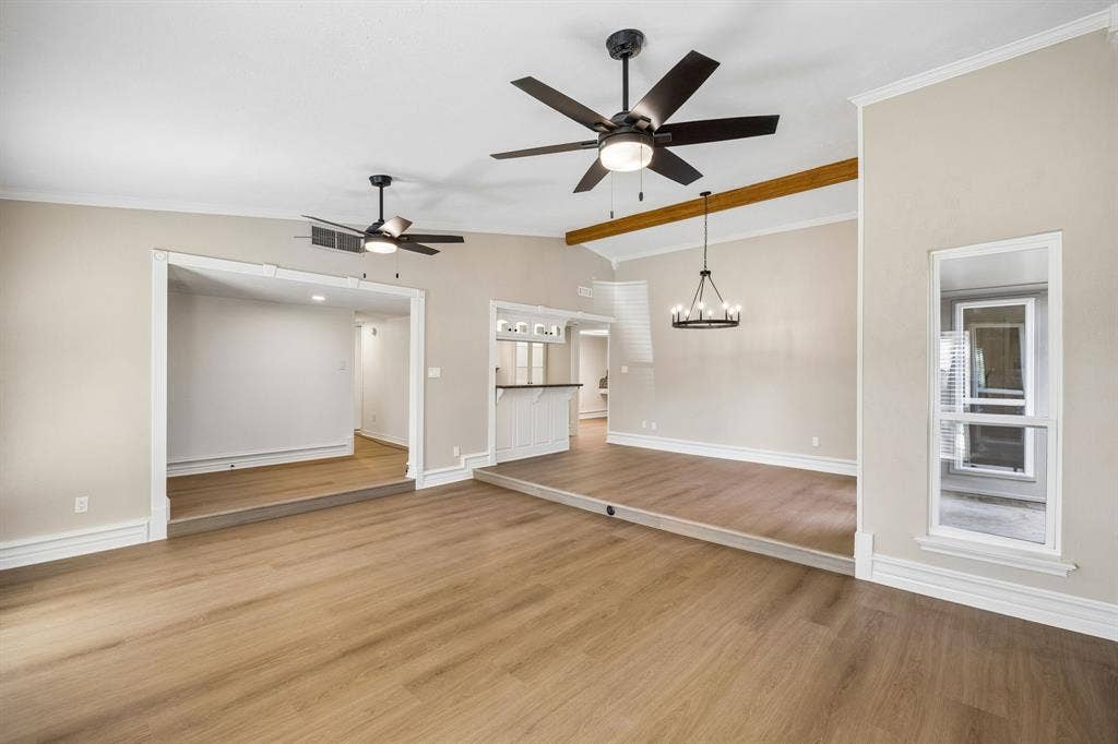 1213 Lombardy Drive, Plano, TX 75023 An open, flowing layout connects the spacious living and dining areas, creating an inviting setting for everyday living and entertaining. Beautiful wood-look flooring extends throughout, complemented by soft neutral walls, decorative trim, and ceiling fans. A raised dining area adds architectural definition, while the distinctive exposed wood beam introduces warmth and character.