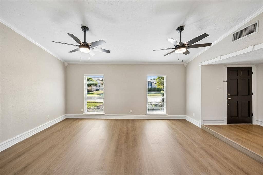 1213 Lombardy Drive, Plano, TX 75023 An open, flowing layout connects the spacious living and dining areas, creating an inviting setting for everyday living and entertaining. Beautiful wood-look flooring extends throughout, complemented by soft neutral walls, decorative trim, and ceiling fans. A raised dining area adds architectural definition, while the distinctive exposed wood beam introduces warmth and character.