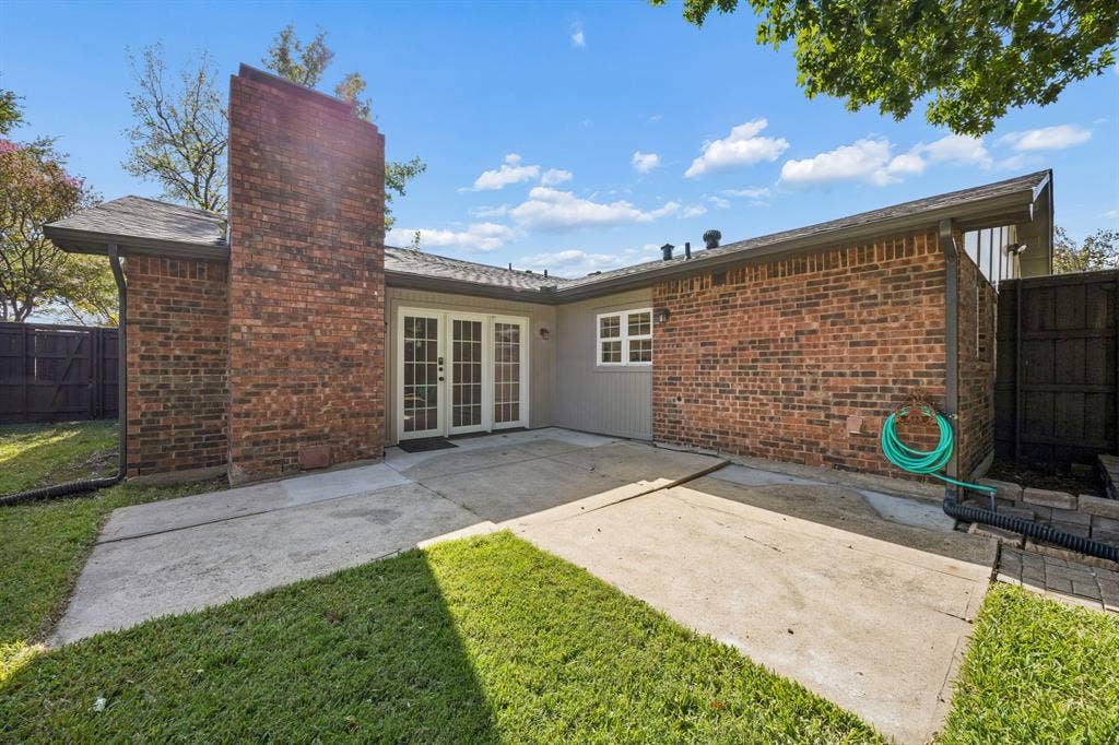1213 Lombardy Drive, Plano, TX 75023 Extend your living space outdoors with this inviting backyard, featuring a spacious concrete patio, classic brick exterior, and charming French doors that connect the interior to the outdoors. The covered section provides a comfortable transition between indoor and outdoor living, while the fenced yard and surrounding greenery offer privacy and room to enjoy the fresh air.