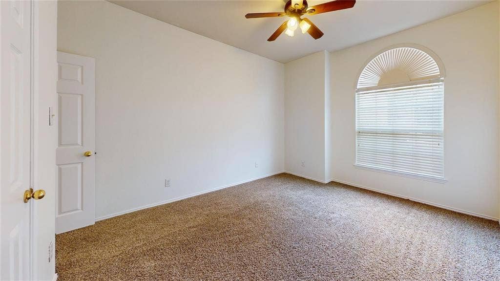 10514 Greenbriar Lane, Rowlett, TX 75089 Room featuring neutral carpeting, an arched window with horizontal blinds, and a central ceiling fan with integrated lighting