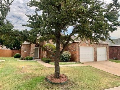 10514 Greenbriar Lane, Rowlett, TX 75089 Brick exterior featuring a two-car garage, concrete driveway, and mature landscaping