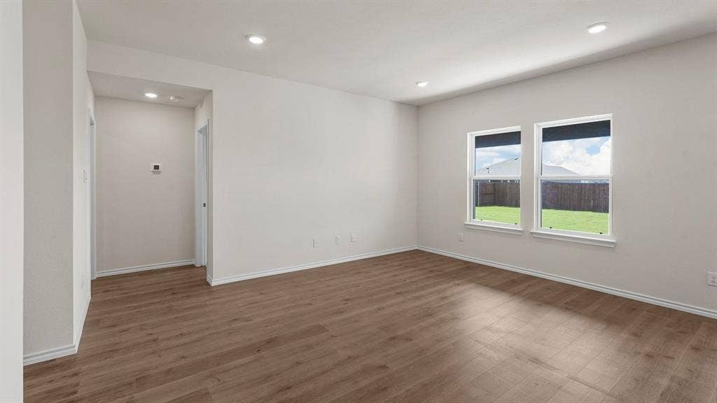 Neutral-toned interior space featuring wood-finish flooring, recessed lighting, and dual windows