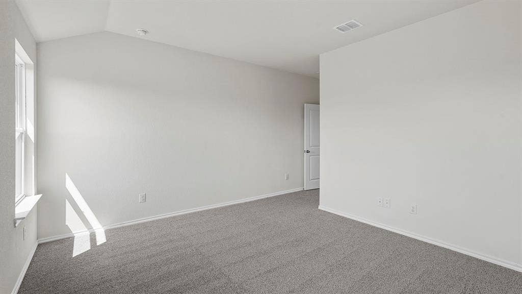 Room featuring a vaulted ceiling, neutral wall tones, window with a sill, and wall-to-wall carpeting