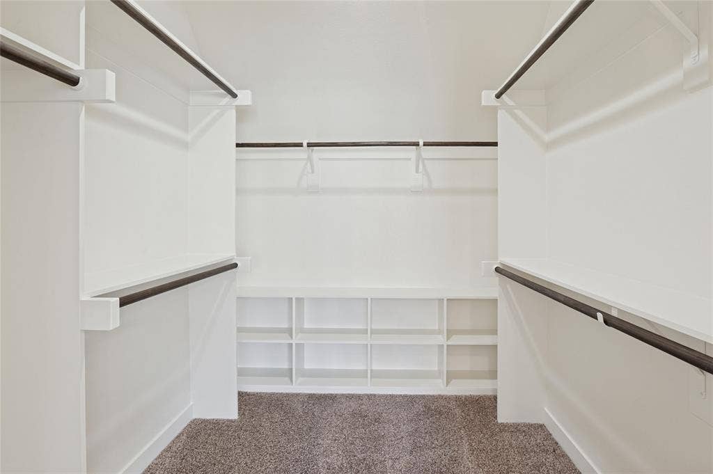 614 Finley Court, Dallas, TX 75208 Walk-in storage space featuring built-in white shelving, multiple tiers of garment rods, and wall-to-wall carpeting