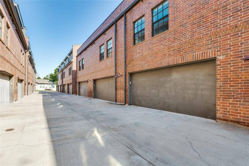 614 Finley Court, Dallas, TX 75208 Red brick exterior featuring multi-pane windows, smooth-finish garage doors, and industrial-style gooseneck wall lighting