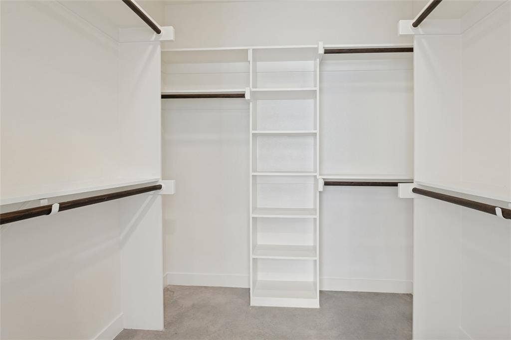 614 Finley Court, Dallas, TX 75208 Walk-in closet featuring white built-in shelving, multiple tiers of hanging rods, and neutral flooring
