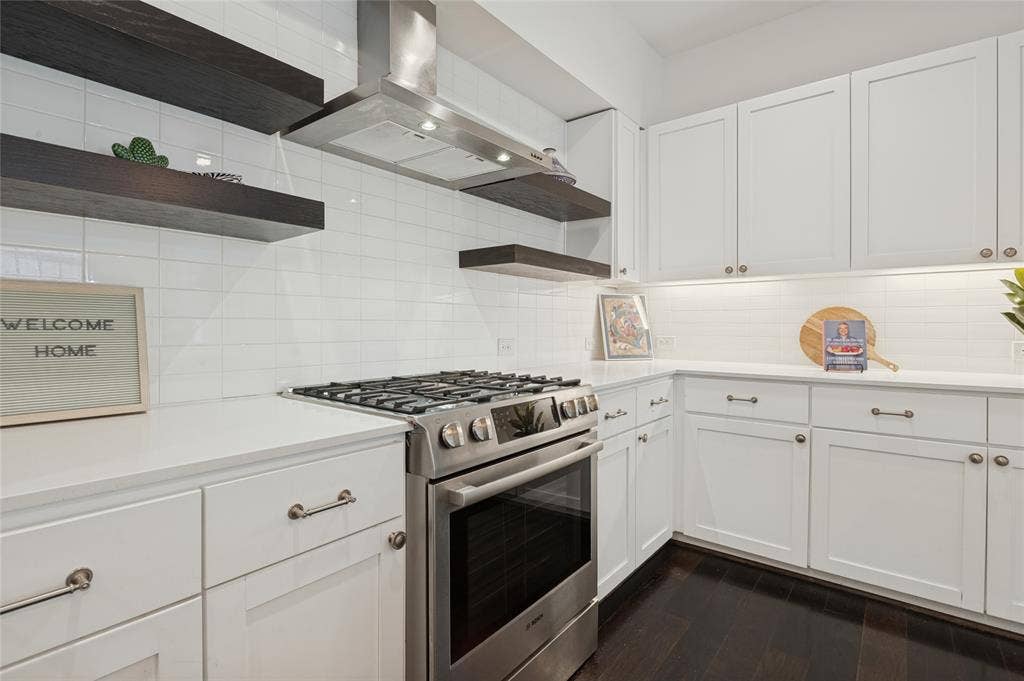 614 Finley Court, Dallas, TX 75208 Kitchen featuring white shaker-style cabinetry, quartz countertops, stainless steel gas range, subway tile backsplash, and dark wood floating shelves