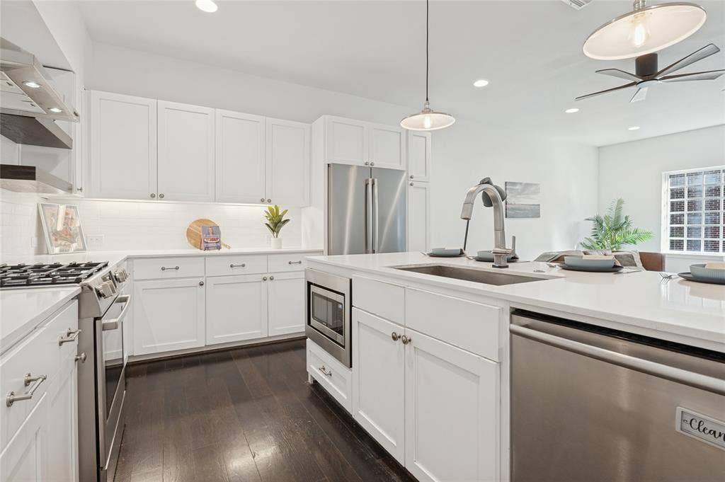614 Finley Court, Dallas, TX 75208 Kitchen featuring white shaker-style cabinetry, quartz countertops, stainless steel appliances, a central island with a built-in microwave, and wood-finish flooring